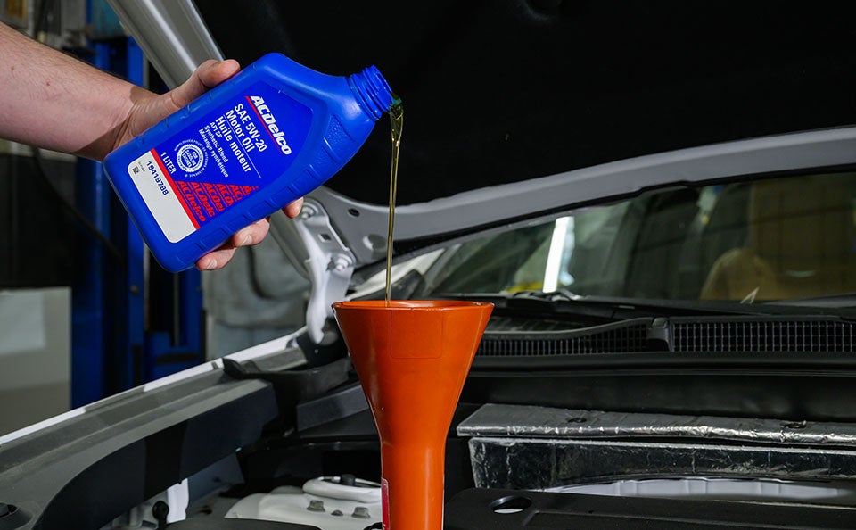A technician pouring engine oil.